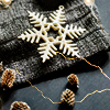 florianschild: a rustic white snowflake on a dark colored colth with a gold wire and pinecones around it (snowflake with pinecones)