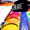 zellieh: A tray of brightly coloured paints and a paintbrush. Text: CREATE (writing: create)